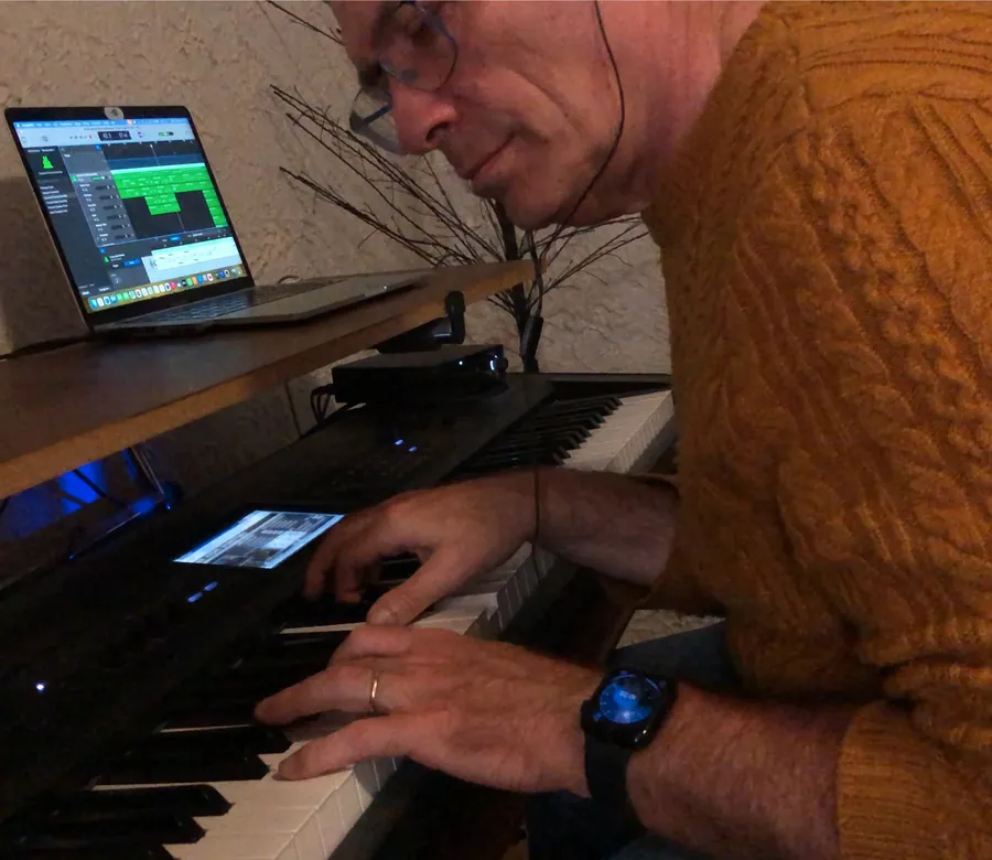 Patrice Skrabal composant de la musique à son synthétiseur, devant son logiciel de composition